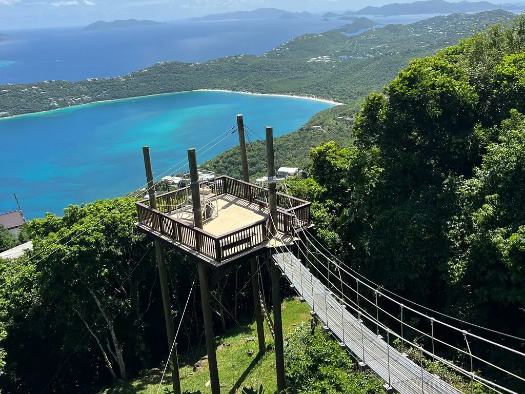 A cable sky bridge leading to a wooden treetop tower